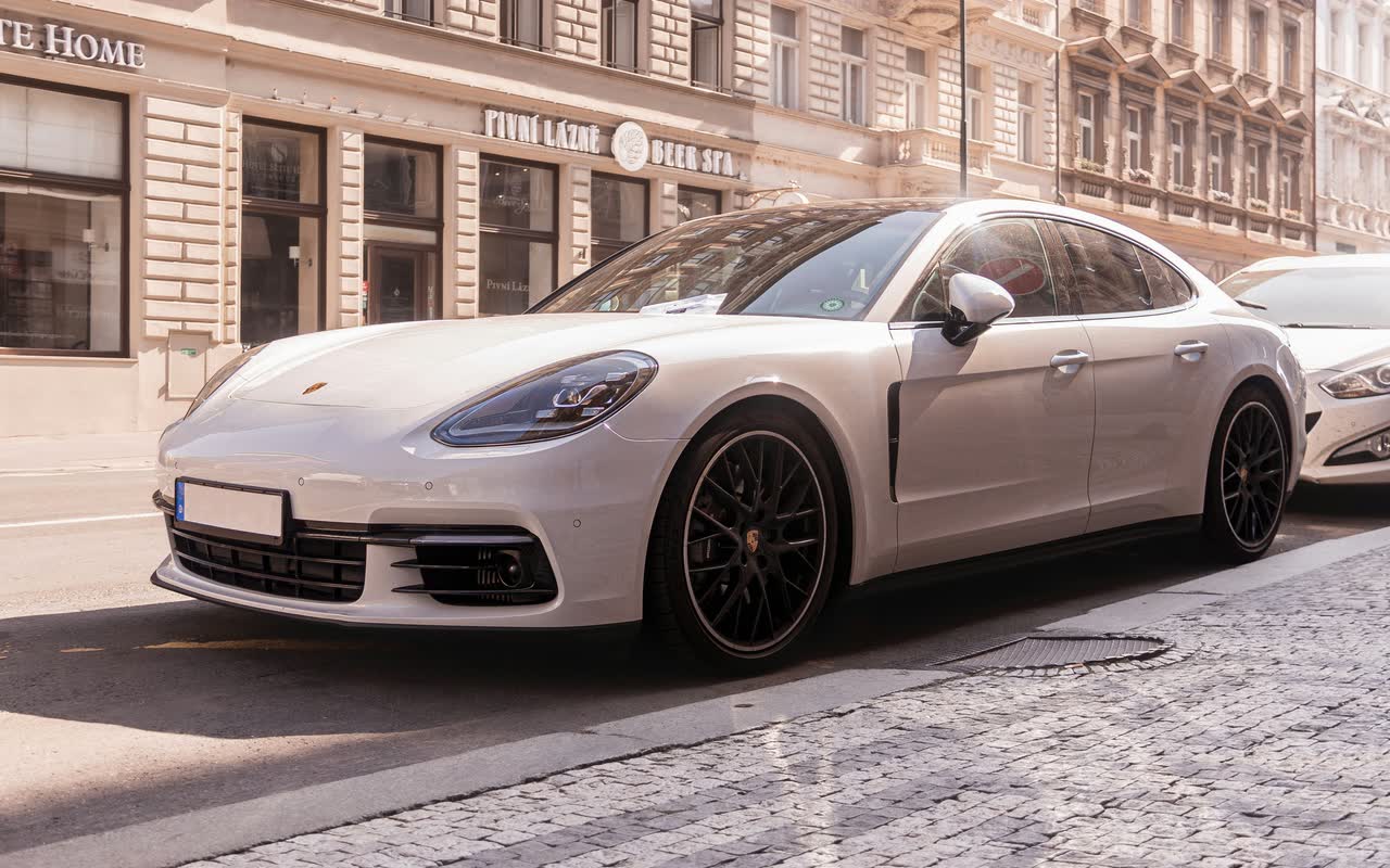 Белый Porsche Panamera у тротуара на улице Праги